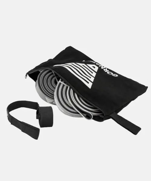 Bandes élastiques de musculation grises enroulées dans une pochette noire zippée, à côté d'une sangle d'ancrage noire